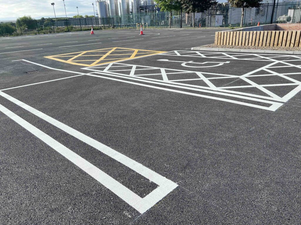 Close-up view of an accessible parking space at FMCI’s proving ground, with high-contrast yellow and white road markings, supporting inclusive mobility solutions and electric vehicle integration. The surrounding area features pedestrian pathways, test track markings, and secure fencing.