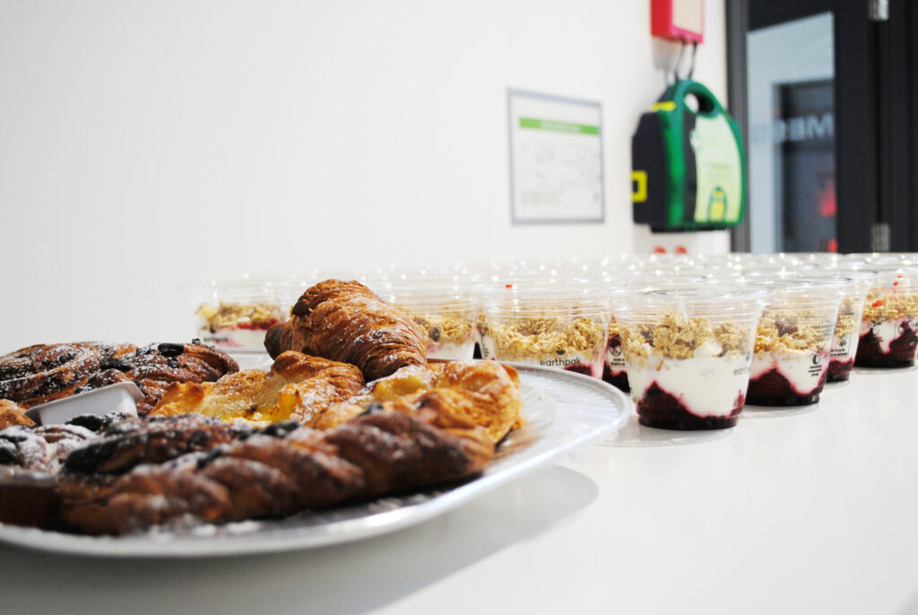 A close-up of a catering table at an FMCI event, showcasing an assortment of freshly baked pastries, including croissants and fruit yogurt parfaits, neatly arranged for attendees.