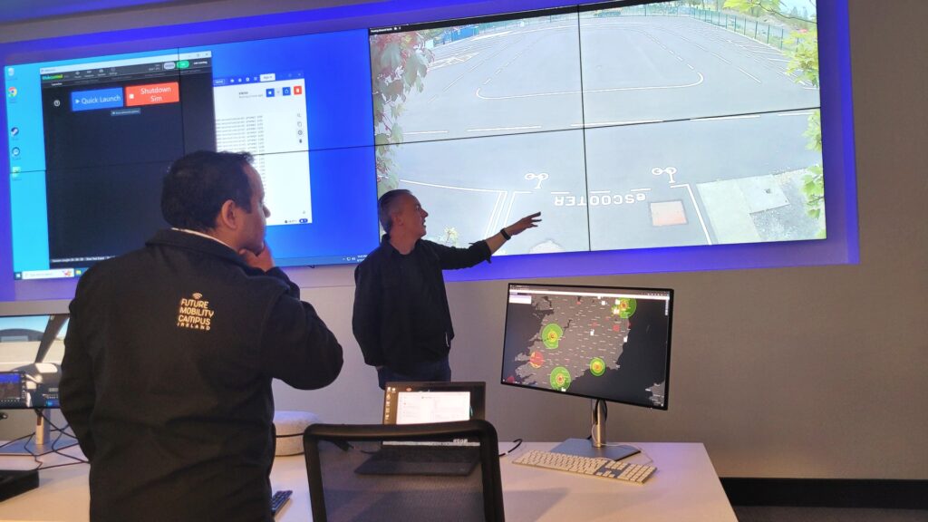 FMCI’s control centre with researchers monitoring real-time proving ground operations. Large screens display live footage of the autonomous vehicle testing site and mobility simulations, supporting connected transport research.