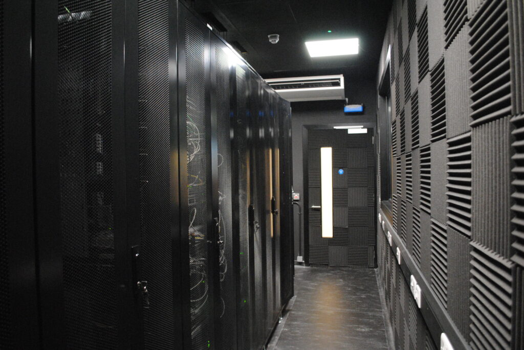 Interior view of FMCI's future mobility research data centre, featuring multiple server racks with advanced computing hardware, including NVIDIA DGX systems for AI workloads. The facility is equipped with high-speed fiber optic connections and robust cybersecurity measures, supporting autonomous vehicle data processing and smart mobility research.