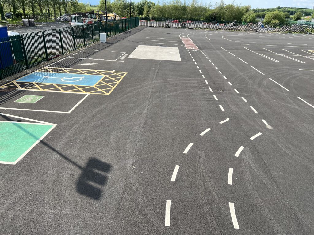 Smart mobility testbed at Future Mobility Campus Ireland (FMCI), featuring multiple road markings, simulated lanes, and designated parking spaces. The test site includes accessible parking, EV charging zones, and marked driving paths with various curve patterns, designed for autonomous vehicle trials and intelligent transport system (ITS) research.