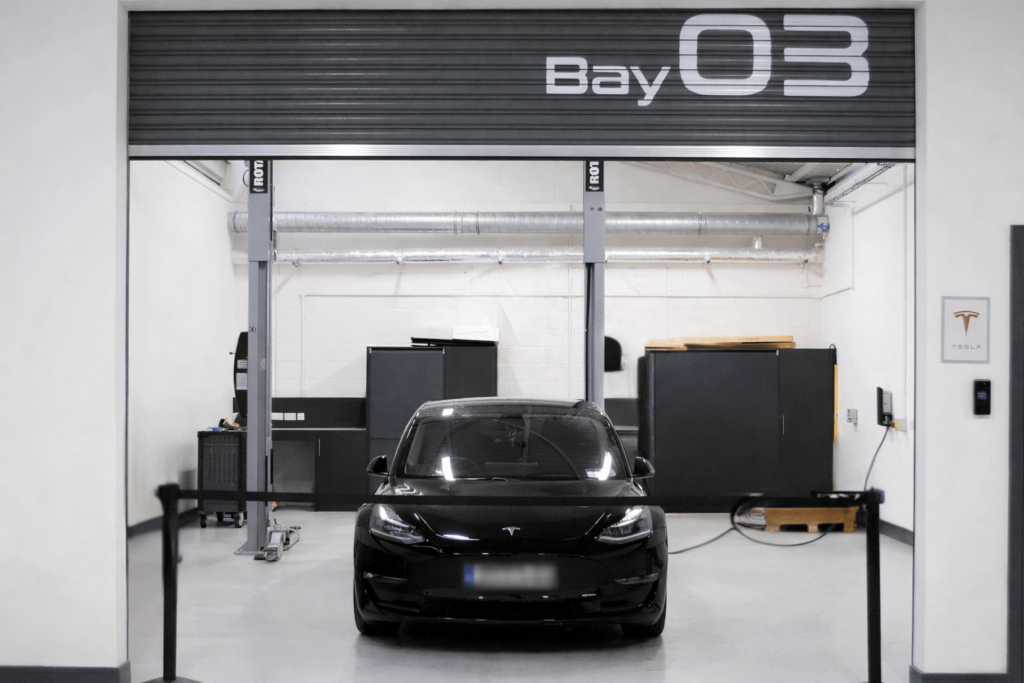 A black Tesla Model 3 test vehicle roped off in Future Mobility Campus Ireland's workshop space. The vehicle is used for smart mobility research, autonomous systems validation, and connected car prototyping.